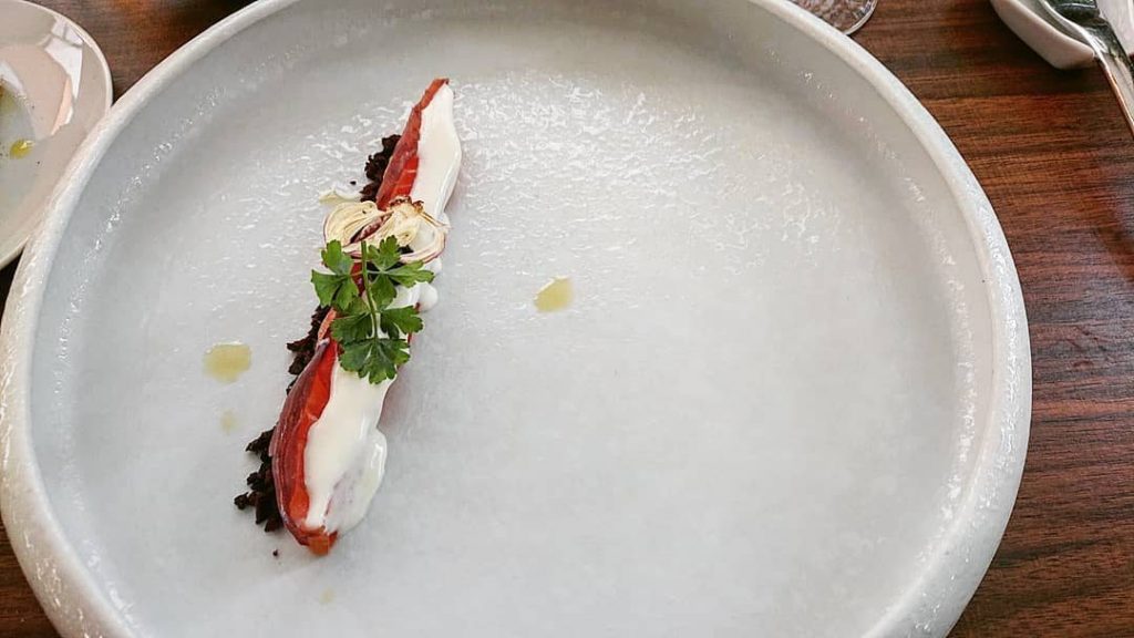 Salmone affumicato in casa, cipolla di Tropea marinata ai quattro aceti, burrata, mirtillo e olive nere